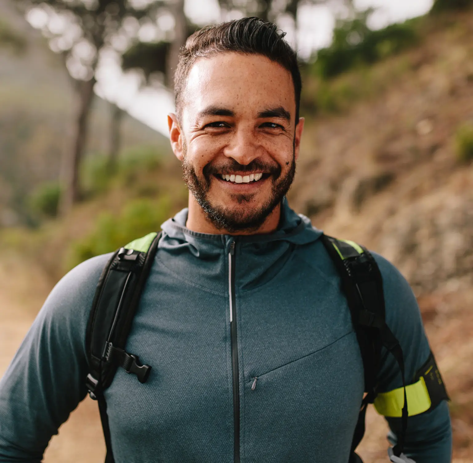Smiling man wearing a backpack outdoors.
