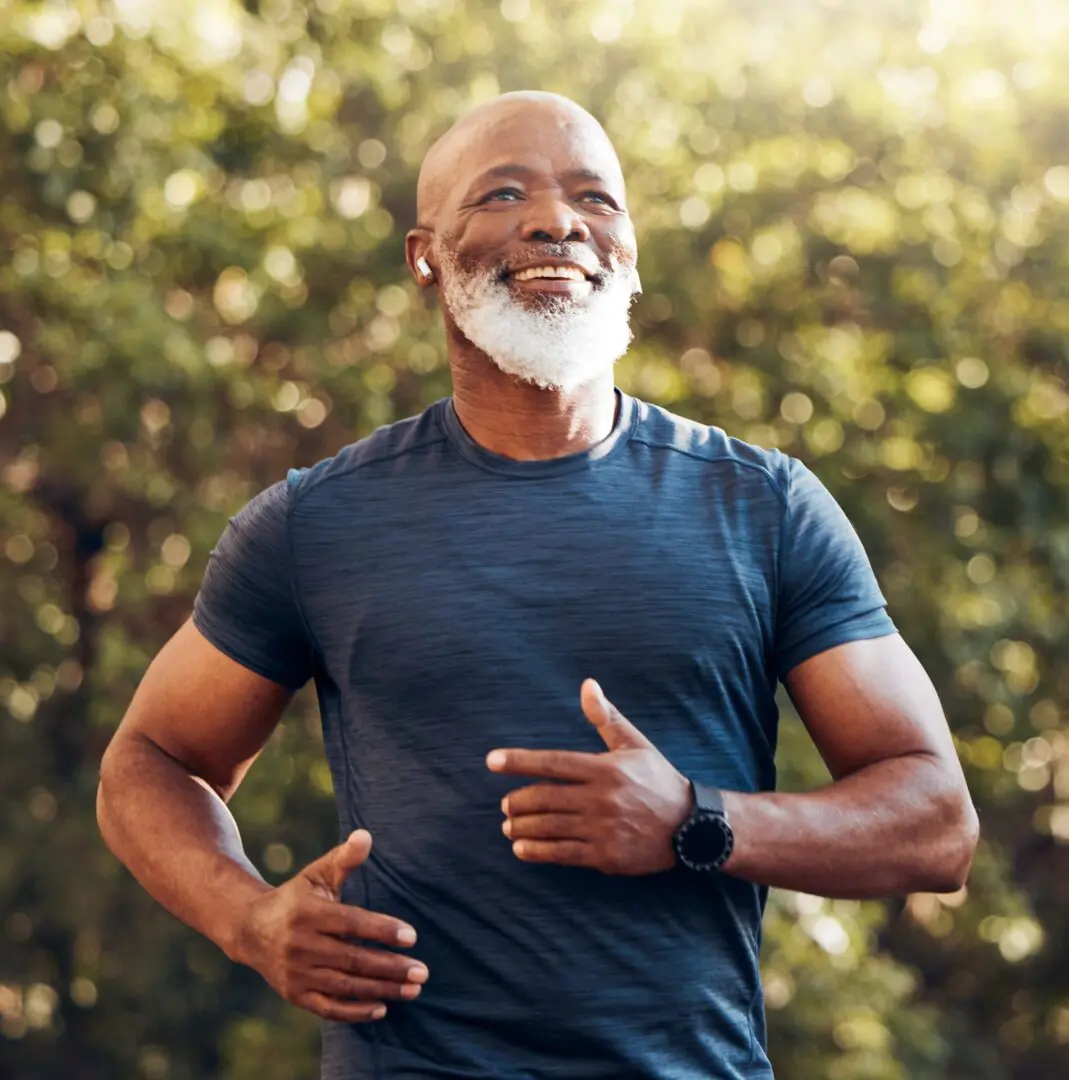 Man jogging outdoors, smiling in sunlight.