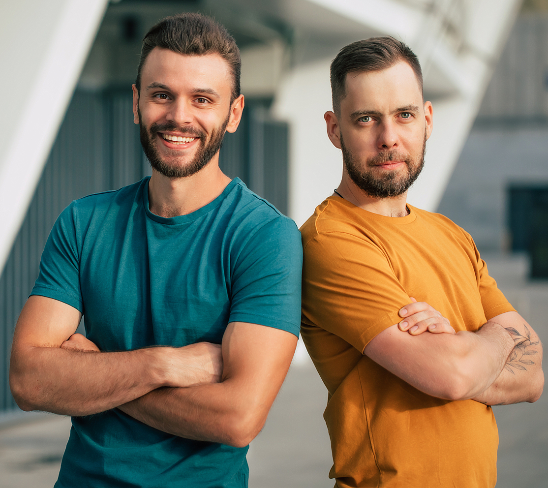 Two men standing with arms crossed, smiling.