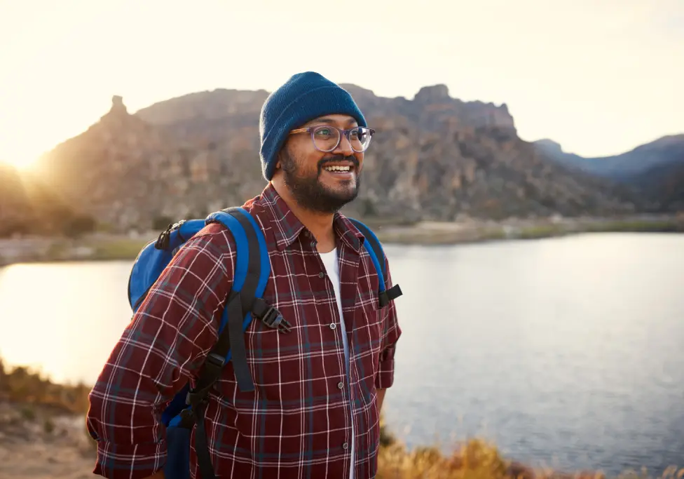 Man hiking by a lake at sunset.