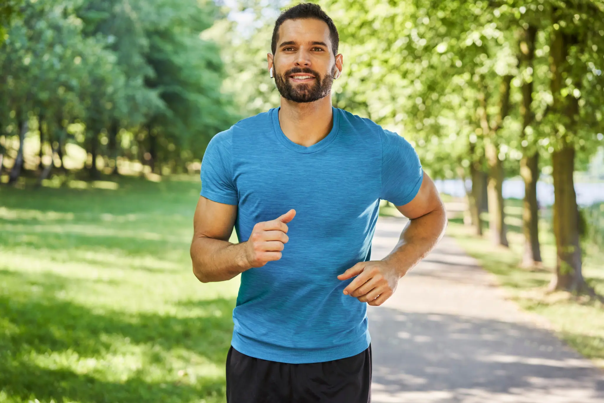 Man jogging on a sunny park path.
